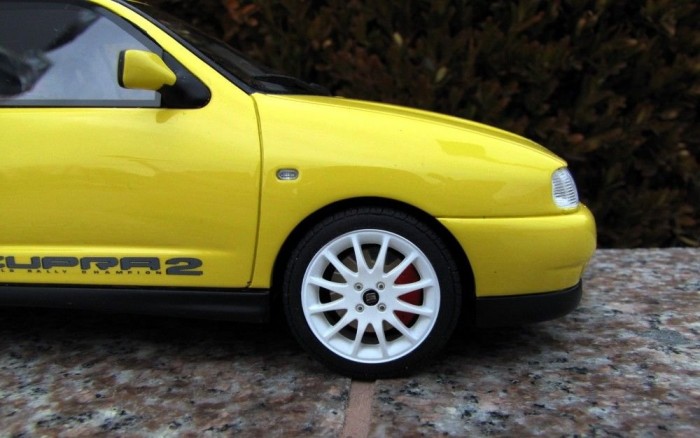 Sárga autón fehér felni mögött piros féknyereg