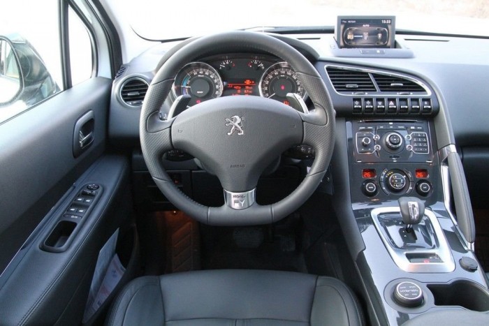 Zöldebb autók Magyarországon 13 | Vezess A pohártartó mellett látszik az üzemmódválasztó tárcsa, a rendszernek Auto, Sport, 4WD és ZEV állása van. Utóbbi az elektromos üzem