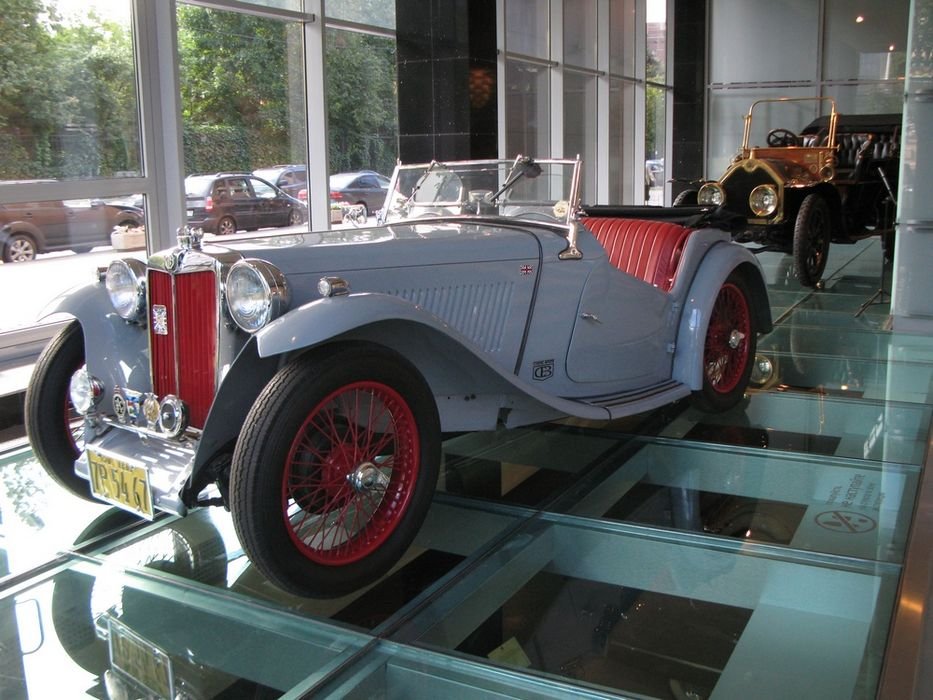 54922_430859_1000x700.jpg | Vezess A második világháború előtti és főleg utáni időszak jellegzetes brit roadstereit gyártotta az MG. Különösen ismert volt a T betűvel jelzett sorozat, amely még a háborút megelőzően kezdte pályafutását. Ez a TA 1938-ban készült, négyhengeres, 50 lóerős motorjával 15,4 másodperc alatt gyorsult százra (ez akkor rakétatempónak számított) és 127 km/órás végsebességre volt képes