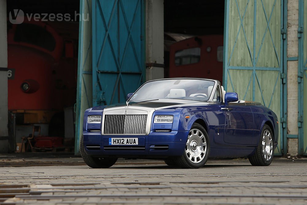 Íme, a Rolls-Royce Phantom Drophead Coupé, a maga 5,6 méteres és 2,6 tonnás valójában. A légies, mozgékony kabriót gőzmozdonyok közé, a Vasúttörténeti Parkba vittük fotózni a visegrádi szerpentin helyett, és szerintünk jól választottunk