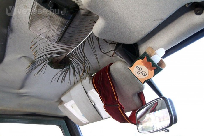 Modern, izléses autóbelső, pávatollal és az Elvarázsolt disznó című meseopera főhősével