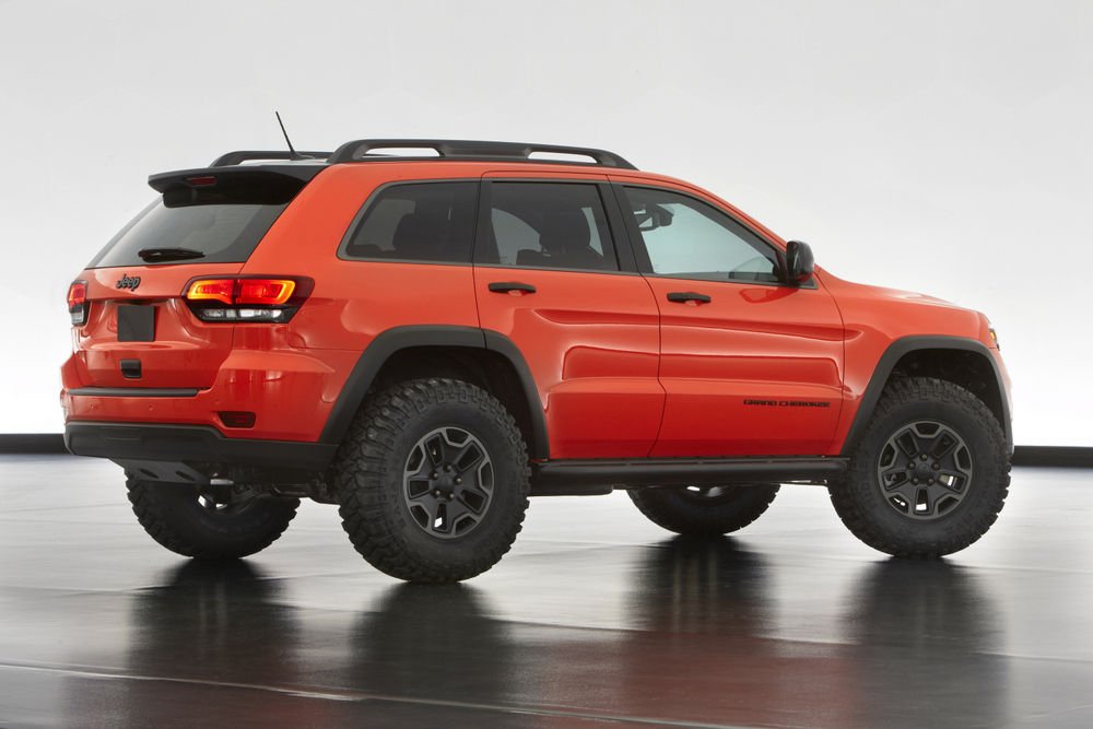 jeep Grand Cherokee Trailhawk Concept - Hathengeres dízelmotorral, de az SRT optikai kiegészítőivel lép színre az extrém Grand Cherokee: mattfekete-vérnarancs fényezés, 35 colos terepabroncsok kivágott kerékjáratokban, egyedi hasvédő lemezek, dupla vonóhorog, Mopar küszöbvédő tereprács.