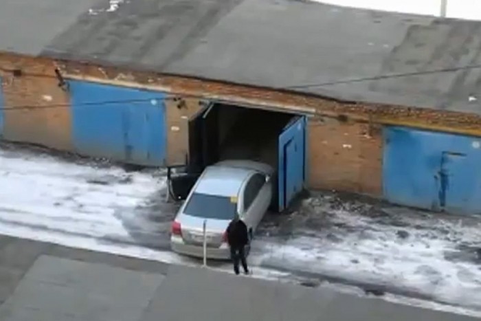 Női sofőr küzdelme a garázsajtóval