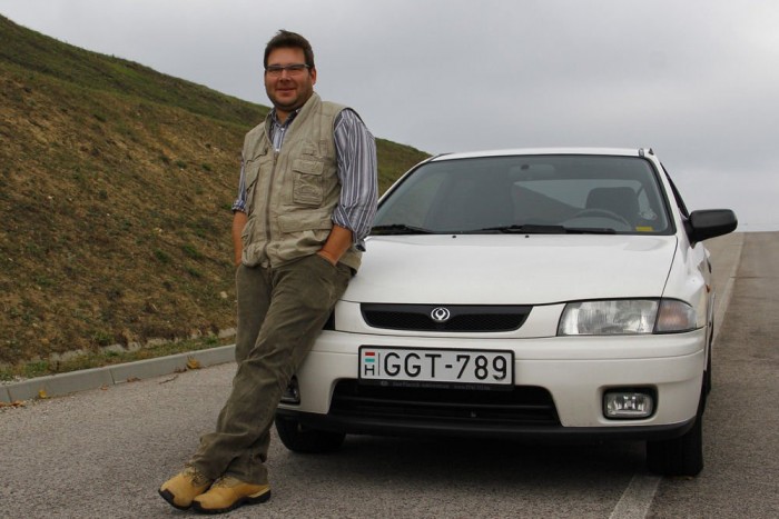 Használt autó: japánt, de olcsón 10 | Vezess A tulajdonos véleménye: Földi D. Attila, Mazda 323P 1,5, 1997, 186 000 km
Nagyon sok Mazdám volt már, most is van egy 323 kombi a fehér mellett. Ezt az autót egy Kia-márkakereskedésből vettem, nem egészen egy éve. Kezdetben 550 000 forintra tartották, de drágasága miatt és mivel nincs benne légkondicionáló, hónapokig várt vevőre. Végül 300 ezer forintért hoztam el. Két korábbi tulajdonosa idején az autó garázsban állt, futásteljesítménye igazolhatóan ennyi.
Rögtön az elején az állástól beállt féktárcsák cseréje 24 ezer forint volt, a munkadíj még tízezer. A 150 ezer km feletti óraállás miatt a kuplungot és a vezérműszíjat is kicseréltettem a biztonság kedvéért. Sajnos a motor nem olyan nyomatékos, mint a 323 kombimban az 1,6-os benzines, pörgetni kell. A rövid áttételezésű sebességváltó miatt autópályán megugrik a fogyasztása, ami Budapesten nagyjából 7,5 l/100 km. Nálam Mazda forever, mert mindig számíthatok rájuk. Bárhová elvisznek hajnalban és bárhonnét hazahoznak éjszaka. Szeretem őket, na.