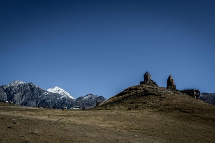 Luxusautóval Azerbajdzsánba 18 | Vezess A Cminda Szameba (Szentháromság), Kazbegi jelképe, egy hegytetőn (2200 m) épült templom. Innen minden irányban olyan látványt nyújtanak a hegycsúcsok, amit még a legdrágább óriás poszterek sem tudtak a nyolcvanas évek nappalijának falán. Órákig, napokig lehetne bámulni, ahogy a rozsdabarna, szürke, kékes vonulatok fehérrel zárt csúcsain táncol a fény.
