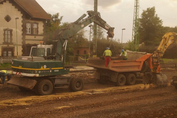Lélegzetelállító tempóban épül a magyar vasút! 8 | Vezess Ketten ráakasztják a kampót a talpfára, ketten leakasztják róla. Holtidő kimaxolva. (Vegyük észre az építkezések jellegzetes motívumát, a melósdekoltázst a kép bal szélén)