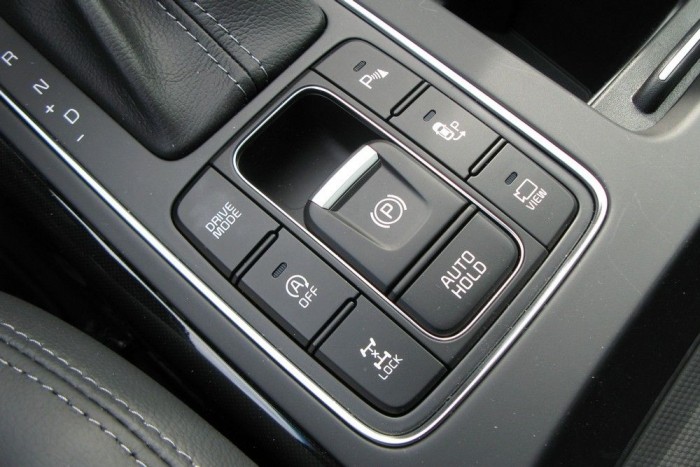 Előzékenységből jeles 9 | Vezess Van itt minden, mint a búcsúban. Felülről, az óramutató járása szerint: parkolóradar kapcsoló, automata beparkolórendszer kapcsoló, 360 fokos kamerarendszer kapcsoló, kézifék, automata befékezőrendszer kapcsoló (lámpánál megállva az automatával nem kell folyamatosan nyomni a féket), váltóprogram-kapcsoló, automata motorleállítás kapcsolója, az összkerékhajtást állandóra kapcsoló gomb