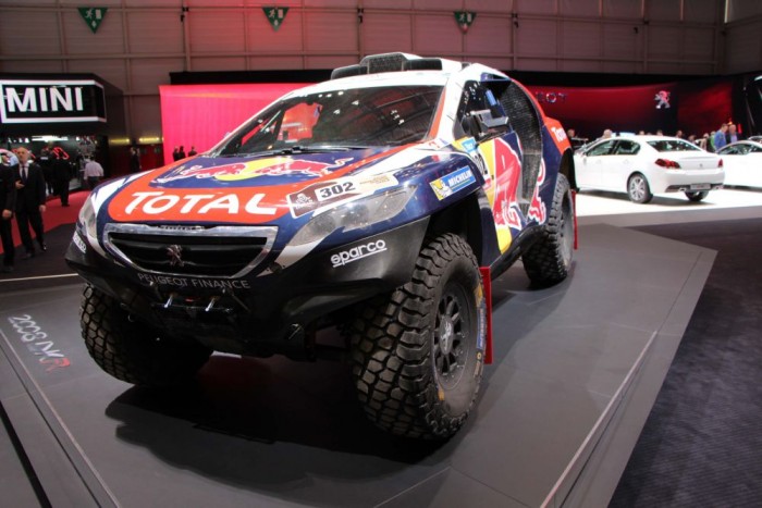 Igazi versenyautók a Genfi Autószalonon 10 Peugeot 2008 DKR - A Peugeot idén tért vissza a leghíresebb tereprali megmérettetésre, a Dakar-ralira. A dizájnerek jó kézzel nyúltak a kisméretű városi járgány formavilágához. Megfelezték az oldalajtók számát, de a 37 colos (94 cm!) kerekeknek köszönhető, hatalmas emelés és a gigantikus aerodinamikai kiegészítők mellett ez a módosítások legkevésbé feltűnő eleme.
A hátul középre beépített V6-os biturbó dízel motor 340 lóerőt, és 800 Nm nyomatékot termel, de hiába a vad külső, és a kiemelkedő teljesítmény adatok, a nagy visszatérés nem sikerült fényesen, a francia gyártó legjobb párosa a Stéphane Peterhansel/Jean-Paul Cottret csak a 11. helyen fejezte be a viadalt.