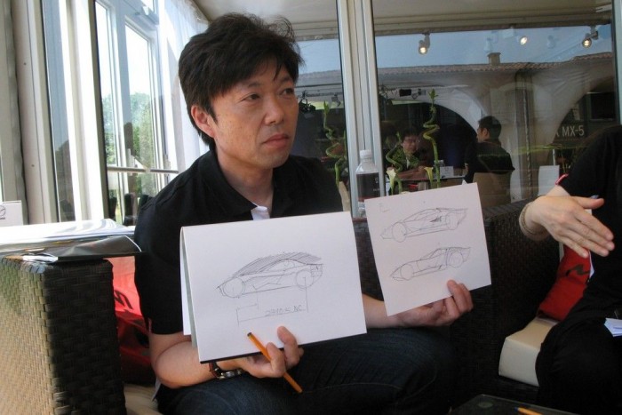 Így lehet kevésből sokat kihozni 10 Masashi Nakayama, az MX-5 fő-fő formatervezője mutatja, hogyan függ össze a ruha és a ruha alatti technika. Bal kezében a középmotoros Lamborghini Countach és Miura rajza, jobbjában az MX-5-ösé. A lényeg: a hajtáslánc, a lámpák, és az utasok helyzete, valamint az előírások eléggé megkötik a tervező kezét, és szinte kiadják az alapformát