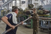 Munkások egy T-80-as harckocsi ágyúcsövét tisztítják a kelet-ukrajnai Harkiv egyik tankjavító műhelyében