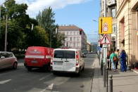 Ez itt a meglehetősen forgalmas József Attila utca. Mögöttünk kezdődik az elegáns Andrássy, balunkra a napsütésben fürdőző deszkás srácokkal teli Erzsébet ér, előttünk valahol a Lánchíd a Dunával, és a szépséges Vár-heggyel – de mi mindjárt jobbra fordulunk a Sas utcába, ahol elautókázunk a Bazilika előtt. Pontosabban mégsem, de ez mindjárt kiderül. Jobbra már jelzik a táblák, forgalmi rend változásra kell számítani