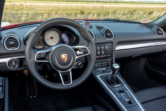 Mit tud egy Porsche négy hengerrel? 5 Mély az üléshelyzet, függőleges a kormány. Újdonság a sok gomb és kapcsoló a volánon, korábban a Porsche nagyon ellenük volt