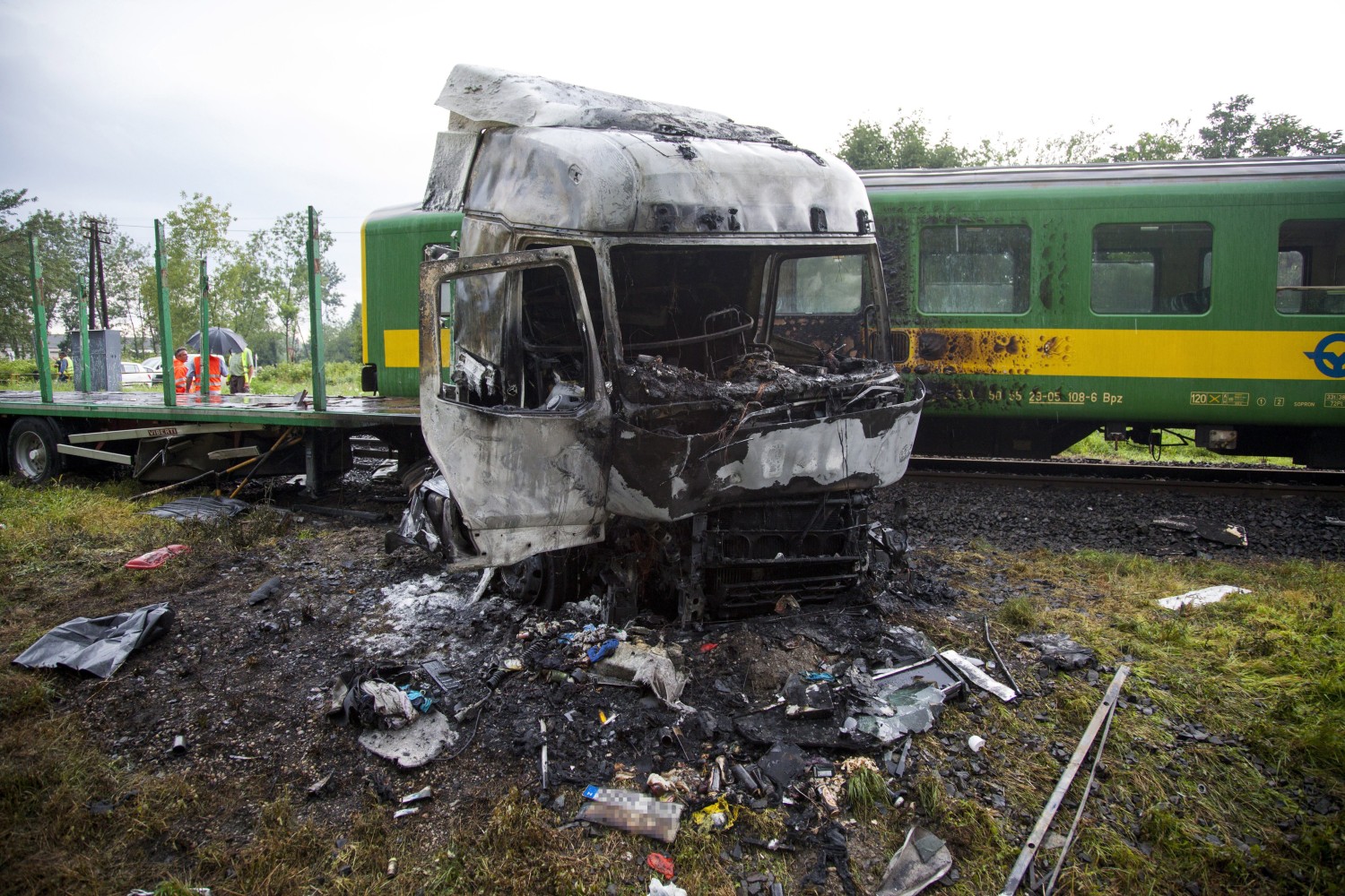 Barcs, 2016. július 25. Összeroncsolódott, kiégett kamion egy személyvonat mellett egy barcsi vasúti átjárónál 2016. július 25-én, miután a két jármû összeütközött. A kamion az ütközés következtében kigyulladt, vezetõje a helyszínen meghalt. A Sopron és Pécs között közlekedõ szerelvény mozdonyvezetõje és egy utasa könnyû sérülést szenvedett. MTI Fotó: Varga György
