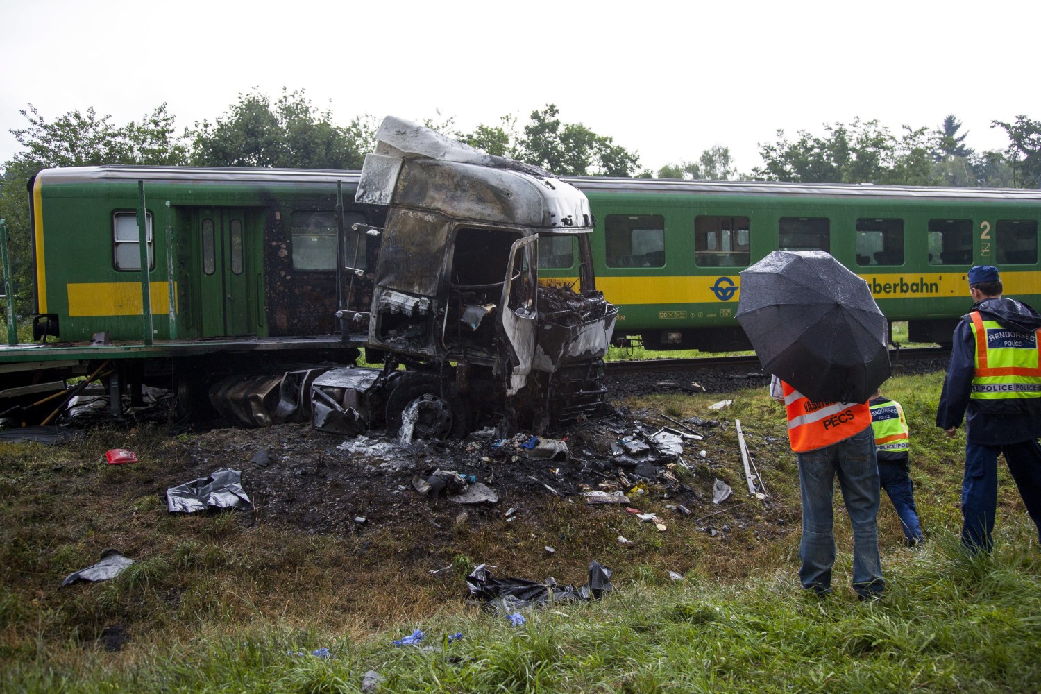 Barcs, 2016. július 25. Összeroncsolódott, kiégett kamion egy személyvonat mellett egy barcsi vasúti átjárónál 2016. július 25-én, miután a két jármû összeütközött. A kamion az ütközés következtében kigyulladt, vezetõje a helyszínen meghalt. A Sopron és Pécs között közlekedõ szerelvény mozdonyvezetõje és egy utasa könnyû sérülést szenvedett. MTI Fotó: Varga György