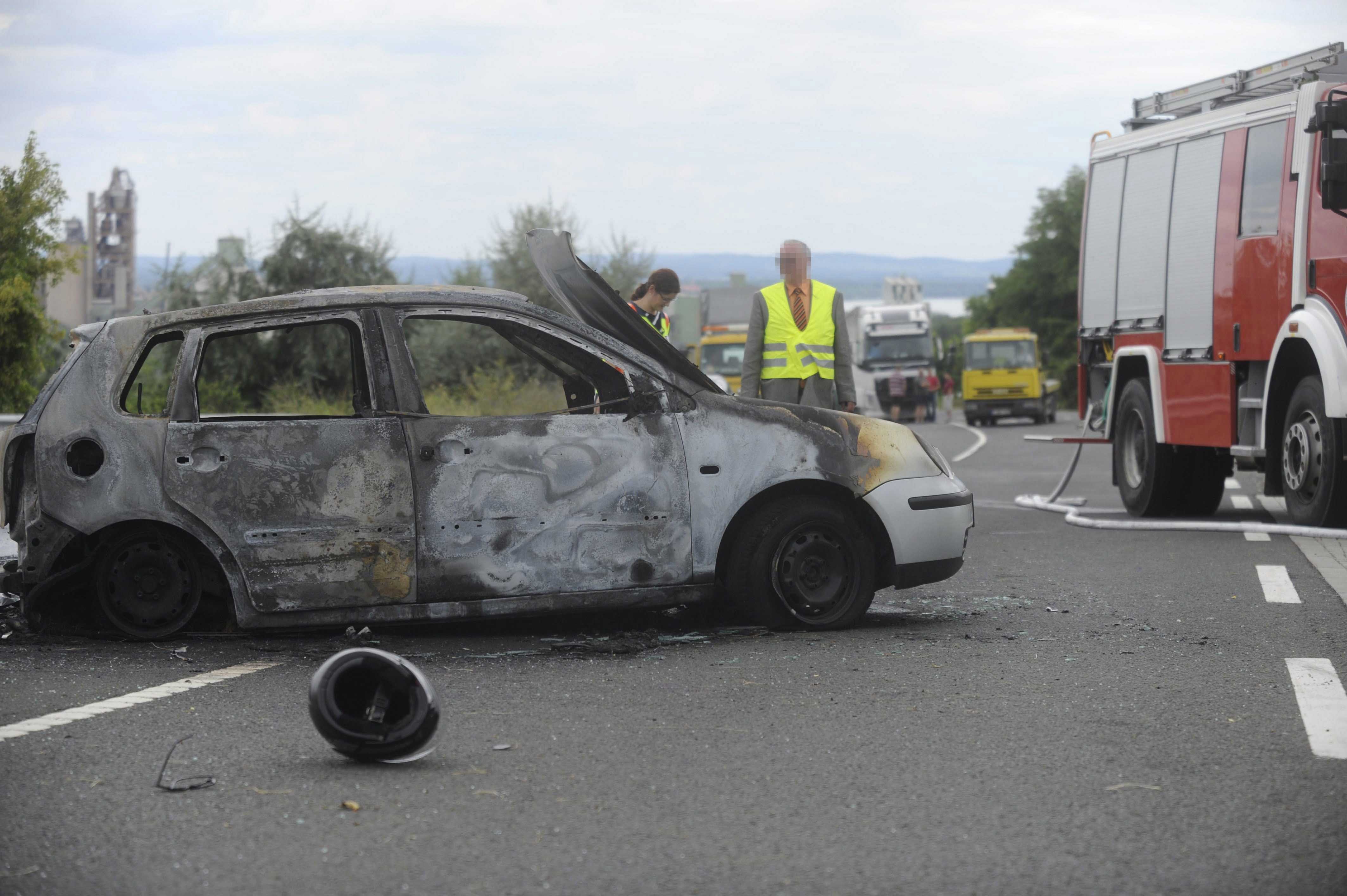 Vác, 2016. augusztus 13. Bukósisak egy kiégett személyautó mellett a 2-es főúton Vác térségében, ahol a személygépkocsi egy motorossal ütközött össze 2016. augusztus 13-án. A balesetben mindkét jármű kigyulladt, a motorkerékpár vezetője életét vesztette, utasa súlyosan megsérült. Az autóban ülők közül egy férfi súlyosan, két nő könnyebben megsérült. MTI Fotó: Mihádák Zoltán