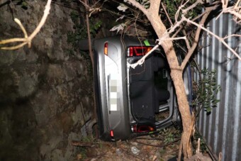 Konténer és kőfal közé zuhant egy autó Budán, fotón a baleset